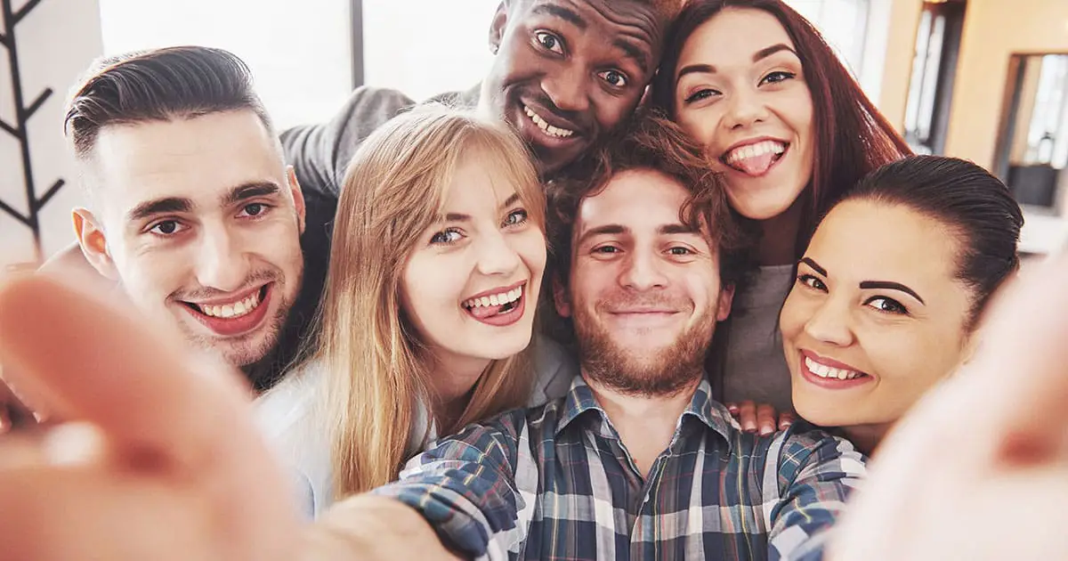 Six young adults smiling and posing closely together for a group selfie indoors, reflecting the positive connections fostered through Choices Psychotherapy and quality mental health services.