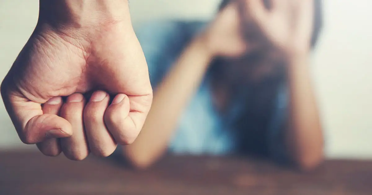 A clenched fist is in the foreground, with a blurred person in the background raising their hands defensively—highlighting the importance of Choices Psychotherapy and mental health services in addressing conflict and emotional well-being.