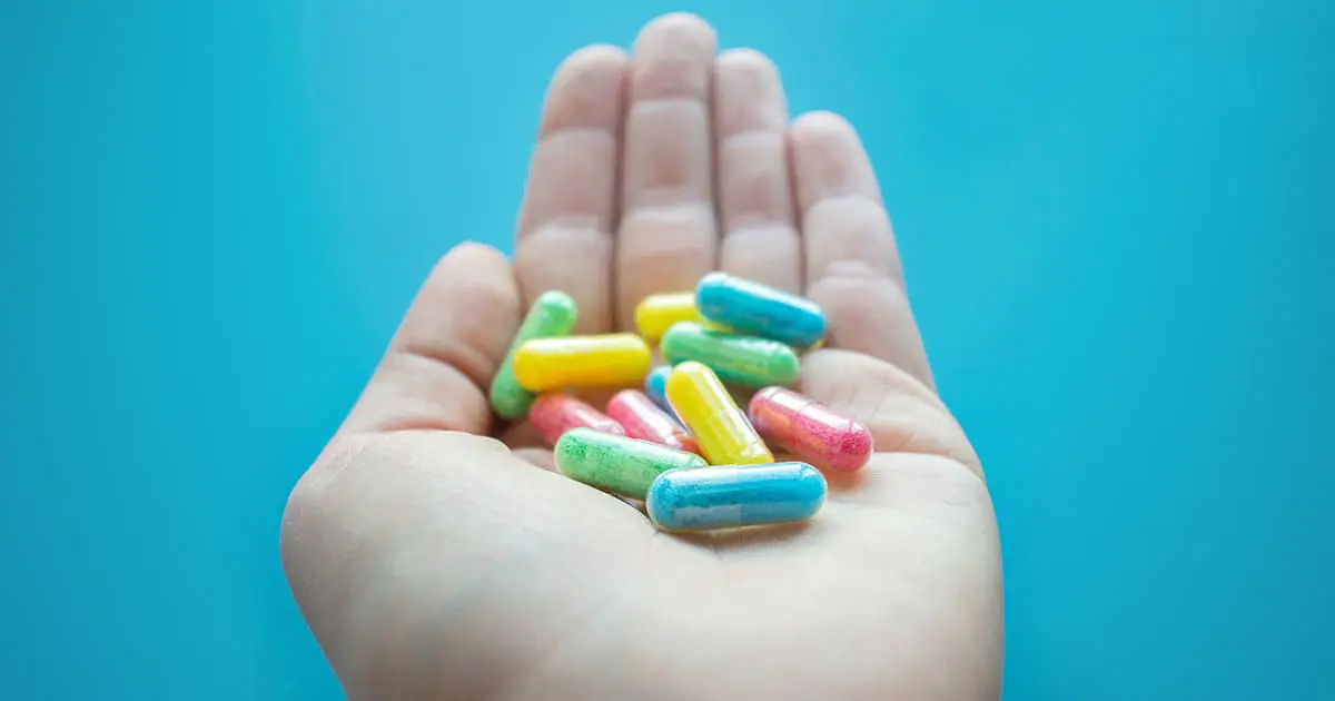 A hand holds several colorful capsules against a solid blue background, symbolizing the range of Choices Psychotherapy and mental health services available.