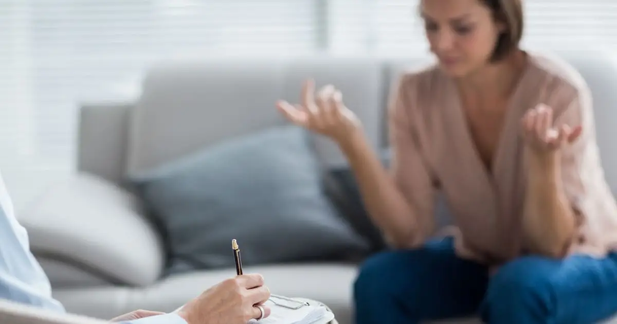 A person sits on a couch gesturing with their hands while another takes notes on a clipboard, reflecting the supportive environment at Choices Psychotherapy and the value of professional mental health services.